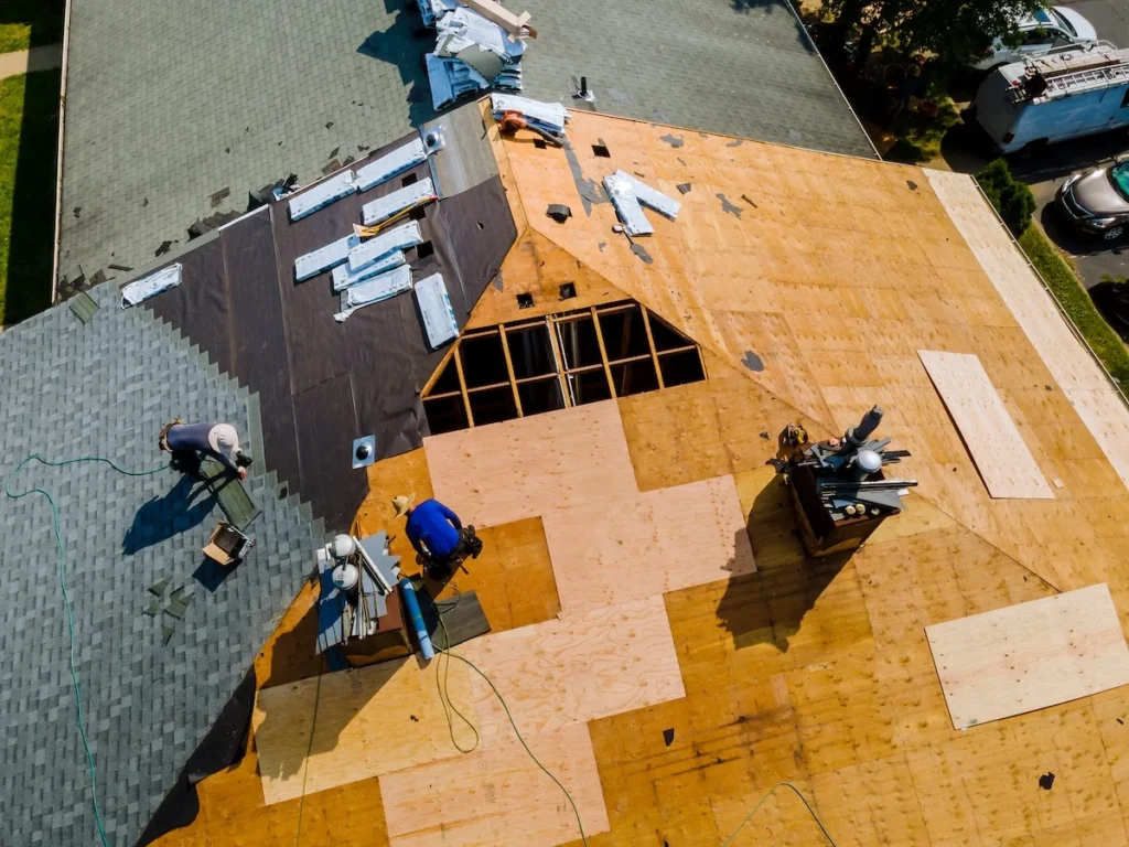 An aerial view of The Roof Tiger team demonstrating how to shingle a roof by installing new plywood decking and underlayment before laying down asphalt shingles.