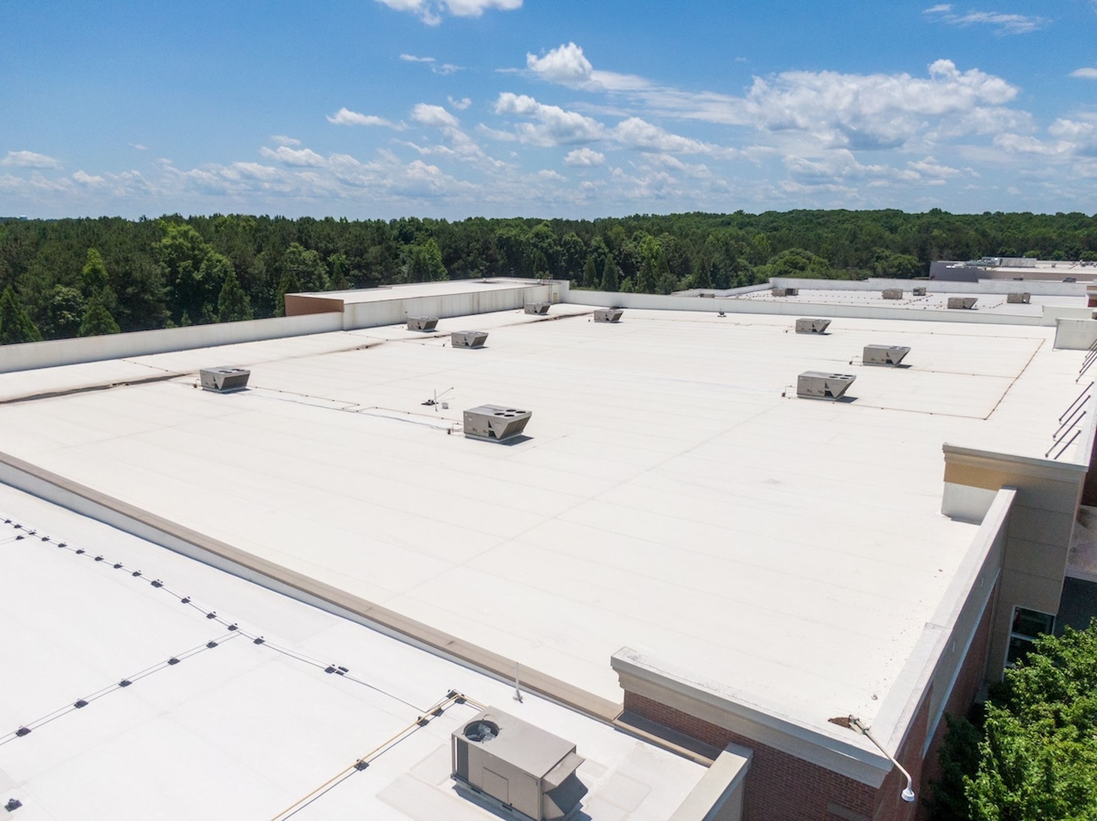 TPO commercial roofing system installed on a large industrial facility, featuring multiple HVAC units and specialized drainage.
