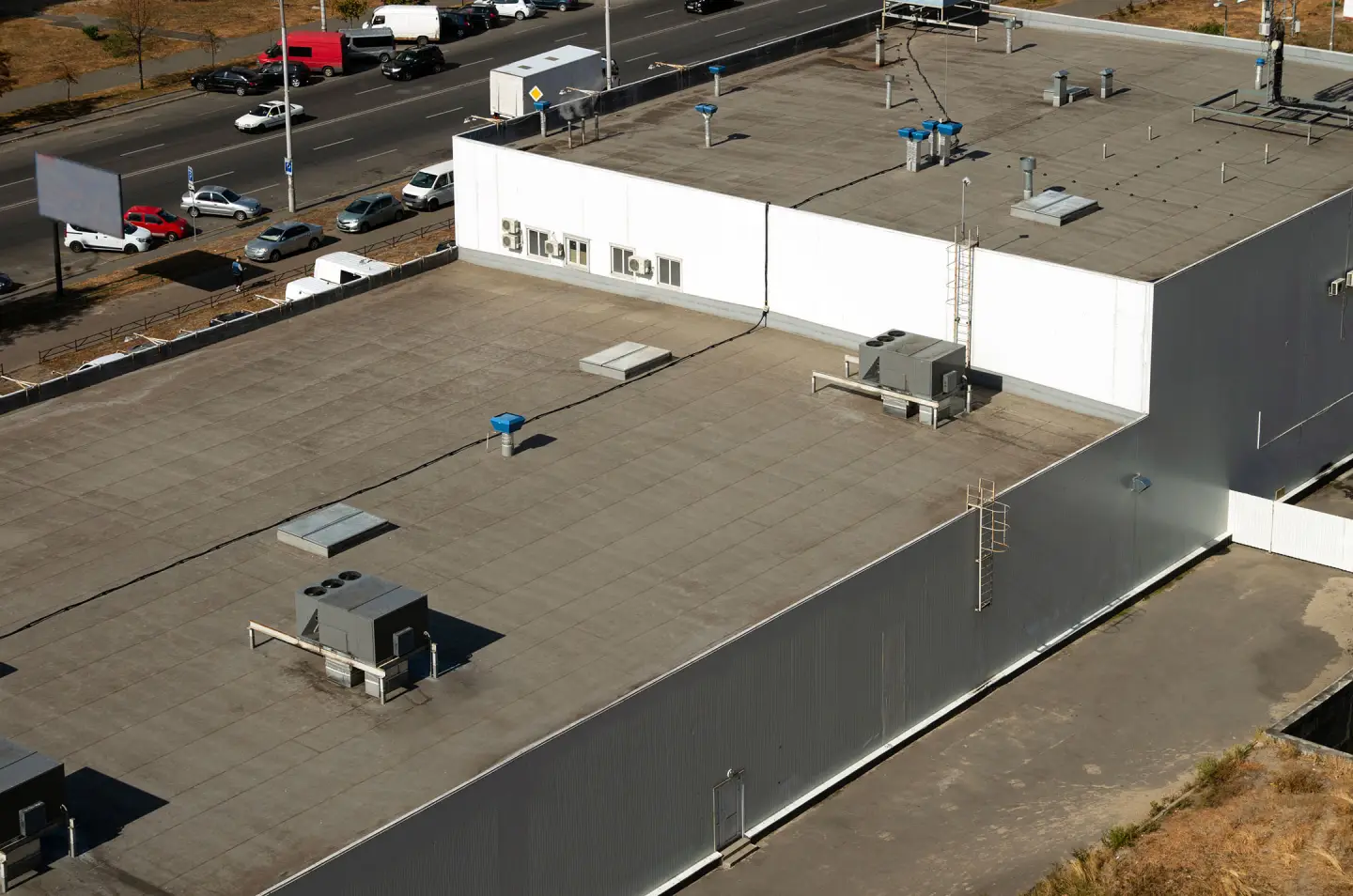 A large-scale industrial flat roof featuring a grey membrane system with multiple HVAC units and specialized ventilation shafts, demonstrating the expansive and high-durability commercial roofing Illinois solutions.