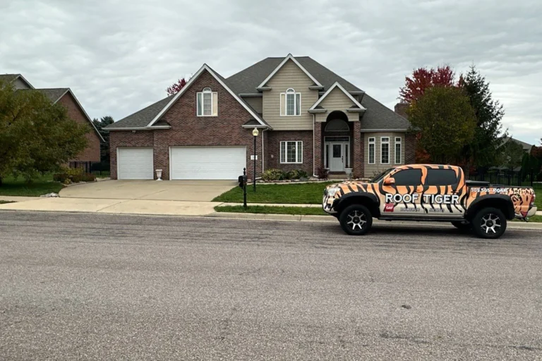 A large brick and siding home featuring a professional residential roofing update, with a tiger-striped ROOF TIGER truck parked out front.