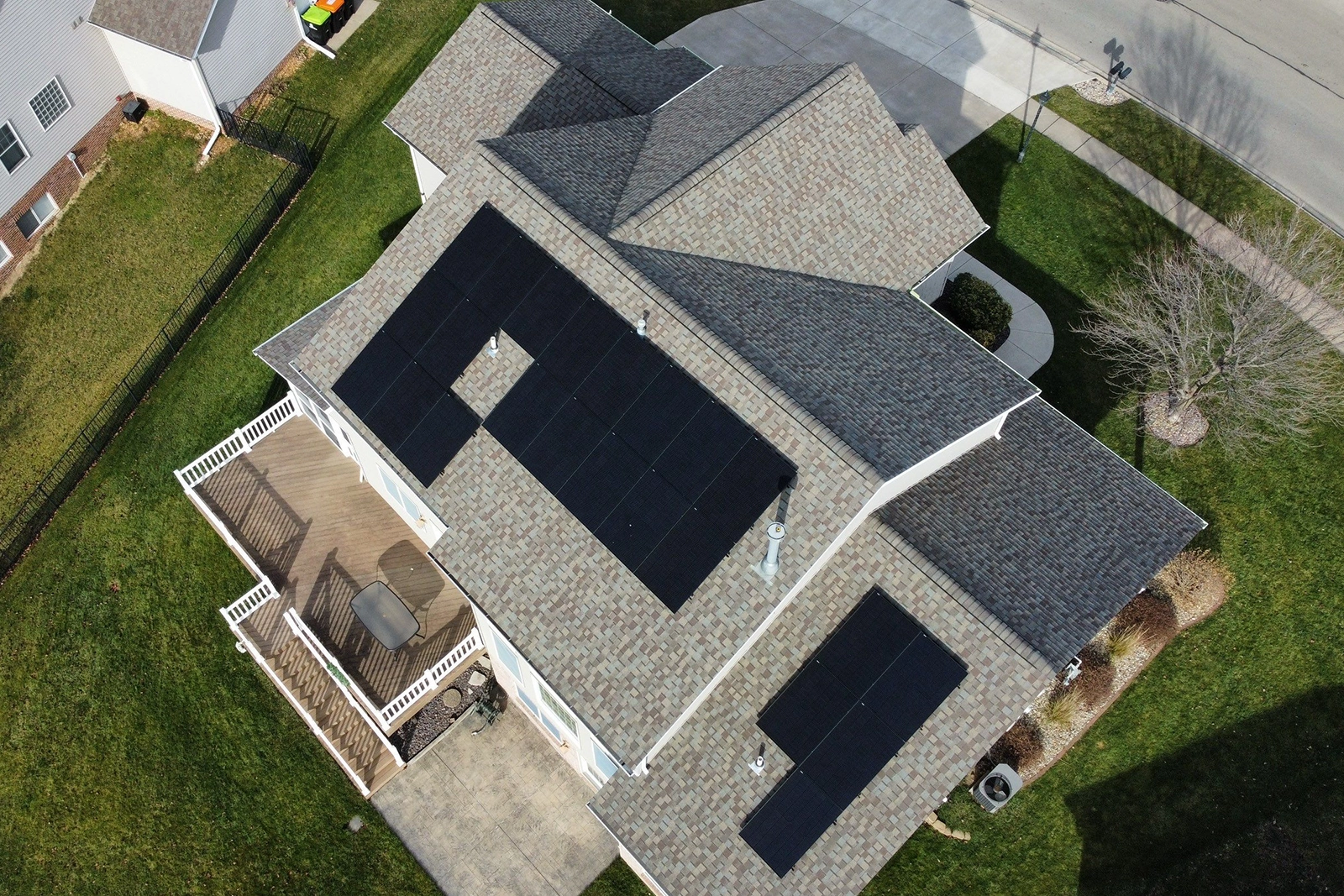 Aerial perspective of a complex light green residential roof with many angles and corners and grey shingles.