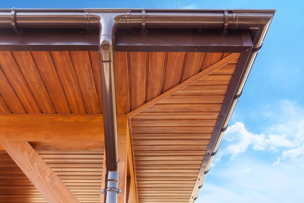 roof overhang Brown copper gutter under a cloudy blue sky