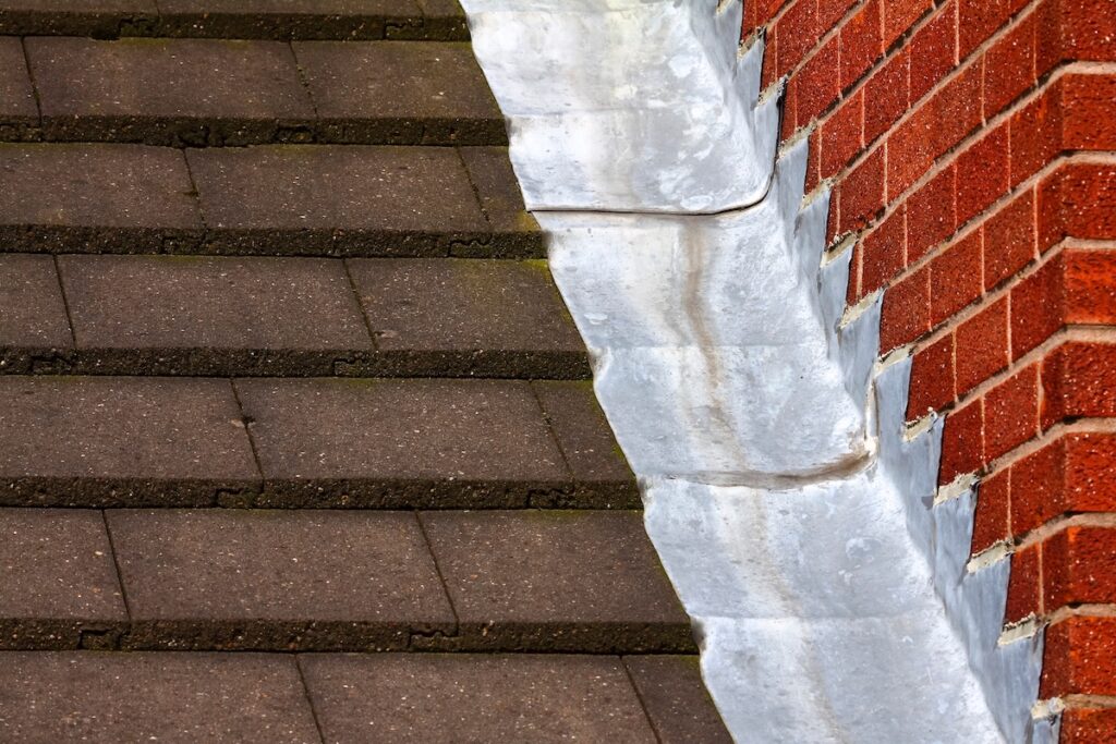roof flashing repair Stepped lead flashing roof gulley creating a water tight seal between roof tiles and brick wall on a domestic house